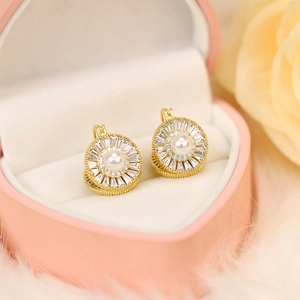 Detailed view of luxury gold earrings with central pearl and radiant baguette-cut zircons