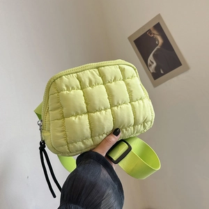 Close-up of a light green quilted nylon crossbody bag with wide strap and zipper detail