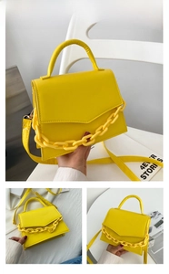 Detail of yellow shoulder bag featuring a V-flap closure and thick decorative chain strap