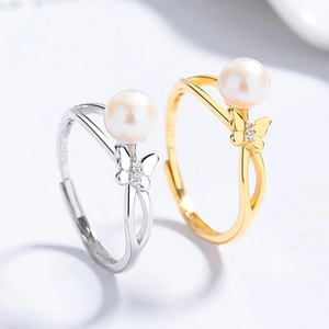 Detailed view of silver and gold butterfly rings with pearls and adjustable S925 bands