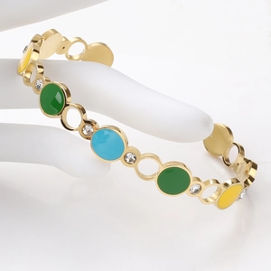 Detail of gold C-shape bangle with colorful enamel circles and white zircon accents