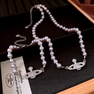 Macro detail of pink pearl necklace with crystal Saturn orb pendant and silver heart tag