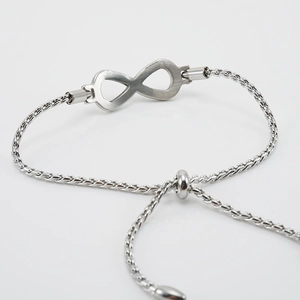 Detail of silver infinity symbol on adjustable stainless steel wheat chain bracelet