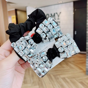 Detail of a black hair tie featuring two bows encrusted with shimmering clear rhinestones