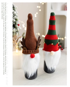 Nahaufnahme von gestrickten Weihnachts-Weinflaschenhüllen mit Wichtelgeweih und Deko