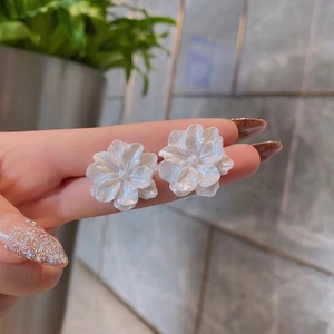 Macro shot of white floral earrings with layered petals being held to show size