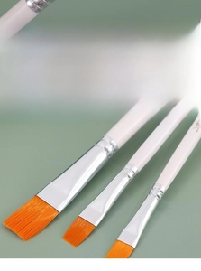 Detailed macro of flat paint brushes with orange synthetic bristles and silver ferrules