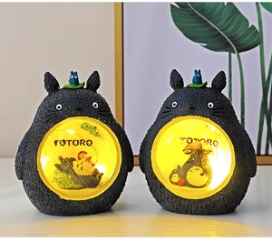 Detail of warm glowing Totoro night lights featuring miniature woodland scenes in round bellies