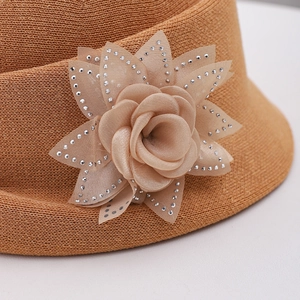 Gros plan sur un chapeau de paille avec fleur en tissu 3D et strass brillants décoratifs
