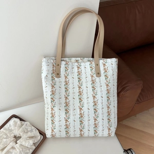 Détail d'un sac cabas floral en coton et lin avec poignées en cuir et rivets en métal
