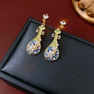 Dettaglio macro di orecchini vintage con smalto blu, strass e perle finte