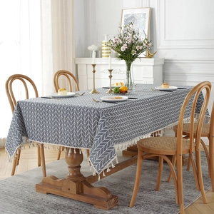 Detail of grey herringbone linen tablecloth featuring white decorative fringe and soft texture