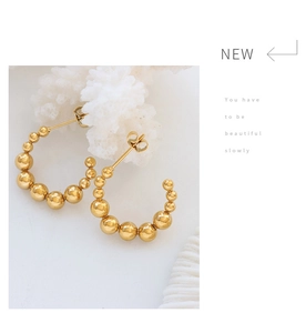 Détail de boucles d'oreilles C dorées avec perles dégradées et fermoir papillon