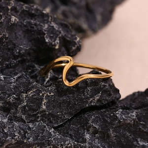 Detail of 18K gold plated wavy ring on a dark rock surface with high gloss finish