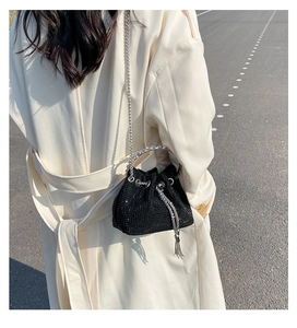 Close-up of black bucket bag with sparkling rhinestones, chain strap, and tassel details