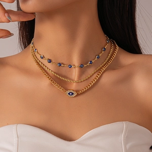 Close-up of layered gold necklace set featuring evil eye charms and rhinestone accents
