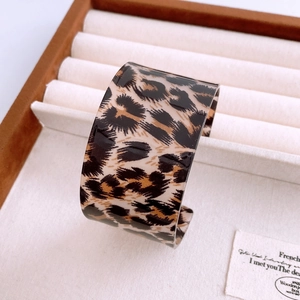 Close-up of wide acrylic cuff bracelet featuring a classic leopard print pattern