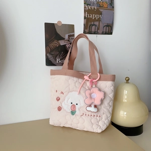 Close-up of pink quilted tote bag featuring a cute dog embroidery and floral plush charm