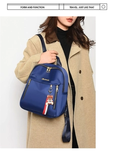 Navy blue oxford backpack with cute bear pendant shown on model wearing khaki coat