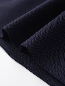 Macro shot of dark blue knit fabric with a textured pique mesh structure and soft folds