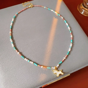 Detailed close-up of beaded unicorn necklace with gold-plated pendant and pearls