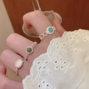 Close-up of vintage silver rings with blue and opal gemstones on hand with lace cuffs