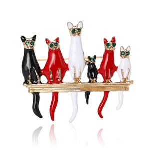 Charming enamel cat brooch featuring six cats on a branch with green gemstone eyes