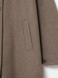 Dettaglio cappotto in lana marrone con trama diagonale a saia e bottone sulla manica