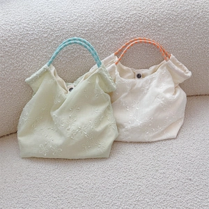 Close-up of floral embroidery on canvas tote bag with colorful braided handles