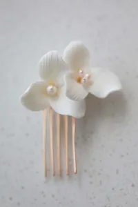 Detailed macro view of white ceramic flowers and pearls on a gold bridal hair comb
