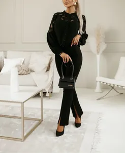 Dettaglio dell'elegante ricamo in pizzo nero sulla camicetta e pantaloni con spacco alto