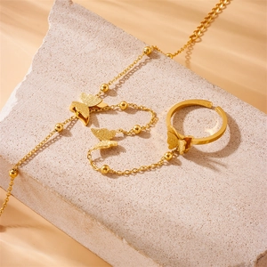 Gold butterfly ring and bracelet set on stone background with chain link design