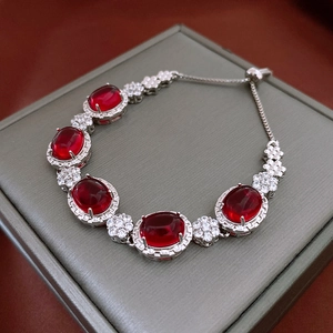 Macro view of gradient red zircon bracelet with oval gems in a premium gray jewelry box