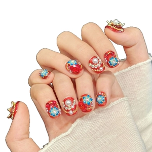 Exquisite red press-on nails featuring blue floral accents, white pearls and sparkling rhinestones