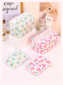 Close-up of quilted floral cosmetic bags with white lace trim and heart-shaped zipper pulls