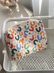 Detail of a floral quilted cotton makeup bag featuring a Sanzokka woven brand label