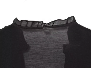 Détail du décolleté arrière avec volants sur une chemise noire en tissu voile
