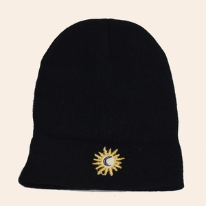 Black knit beanie with sun and moon embroidery, cozy winter hat on a plain background