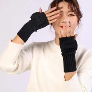 Close-up of black knitted fingerless gloves with a vertical ribbed pattern and cute bow