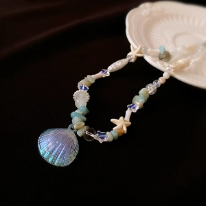 Macro view of ocean-style necklace with iridescent shell pendant and starfish beads