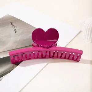 Macro view of bright magenta heart hair claw clip with glossy finish on white surface