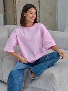 T-shirt rosa in cotone vestibilità comoda abbinata a jeans su un divano grigio