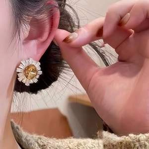 Daisy stud earrings with white petals and gold center shown on a model ear