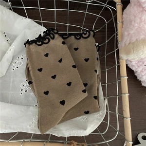 Detail of khaki knit socks with black heart pattern and ruffled elastic lettuce edges