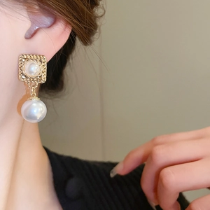 Detailansicht von Vintage-Goldohrring mit quadratischer Perle am Ohr des Models