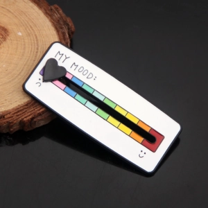 Detail shot of rectangular rainbow mood slider pin with heart marker on white enamel finish