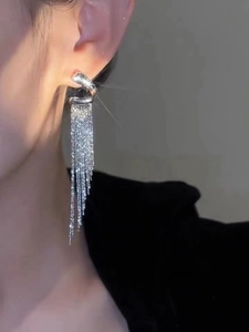 Close-up of elegant silver tassel drop earrings on model with shimmering metallic finish