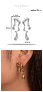 Detail view of liquid metal earrings showing size dimensions and golden finish on ear