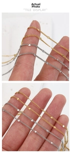Detail of 18k gold and silver stainless steel sequin chains wrapped around a finger