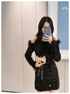 Detail of black sequin dress with feather trim and golden bow evening clutch bag